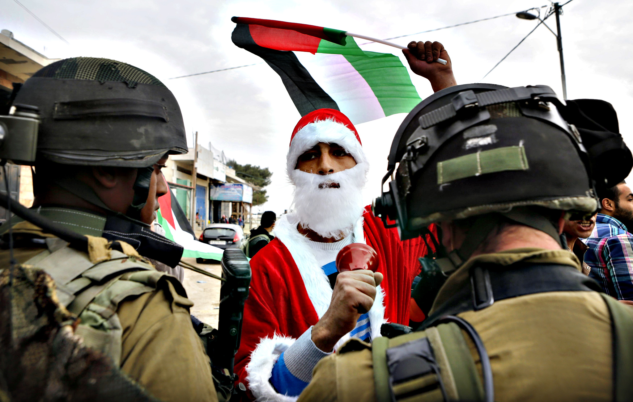 Palestinese vestito da Babbo Natale durante manifestazione contro l'occupazione (Foto Musa Qawasma-Reuters)